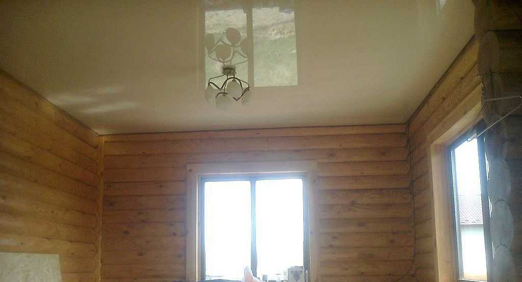 Глянцевый натяжной потолок в доме из бревна